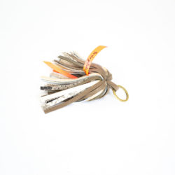 Close-up of the product: a keyring with beige and light gold leather fringes.